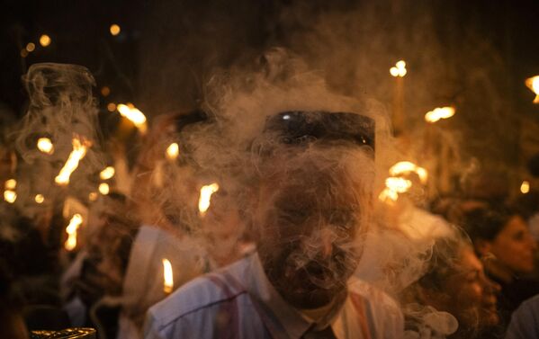Ortodoxní kres?ania sa stretávajú so zapálenými svie?kami po?as obradu Svätého oh?a v kostole Svätého hrobu v Jeruzalemskom Starom meste v predve?er Ve?kono?nej nedele.  - Sputnik International