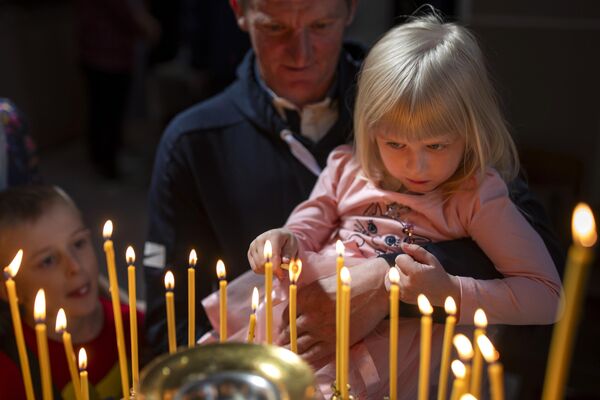 Veriaci zapaľujú sviečky po ceremónii požehnania torty a veľkonočných vajíčok v pravoslávnom kostole Svätého Ducha v litovskom Vilniuse. Veriaci zapaľujú sviečky po ceremónii požehnania torty a veľkonočných vajíčok v pravoslávnom kostole Svätého Ducha v litovskom Vilniuse. - Sputnik International