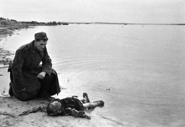 Sovietsky vojak na brehu rieky Dnepr smúti za zavraždeným dieťaťom. Sovietsky vojak na brehu rieky Dnepr smúti za zavraždeným dieťaťom. - Sputnik International