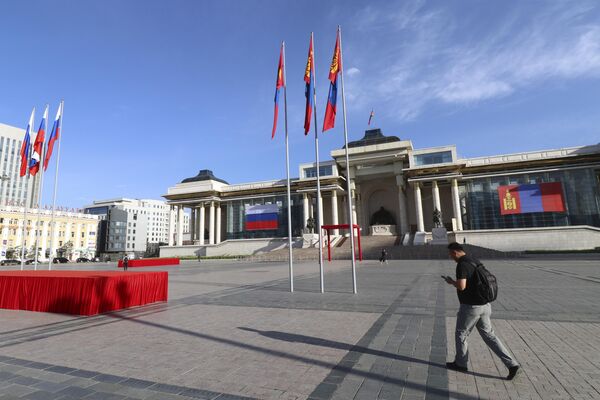 Muž prechádza okolo námestia Sukhbaatar, zdobeného štátnymi vlajkami Mongolska a Ruska. Muž prechádza okolo námestia Sukhbaatar, zdobeného štátnymi vlajkami Mongolska a Ruska. - Sputnik International